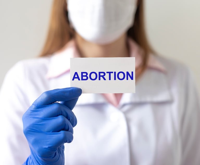 Doctor woman in protective gloves holds a paper with text abortion